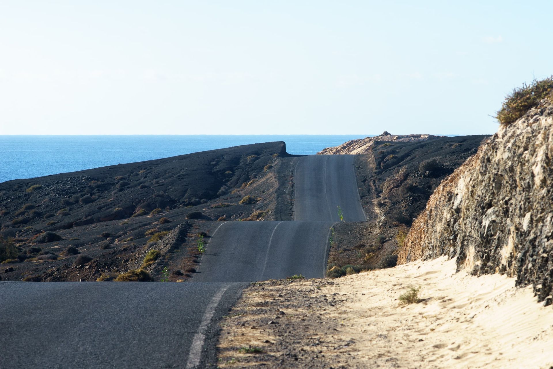 Winding road through the volcanic landscape of Fuerteventura, leading down to the sea